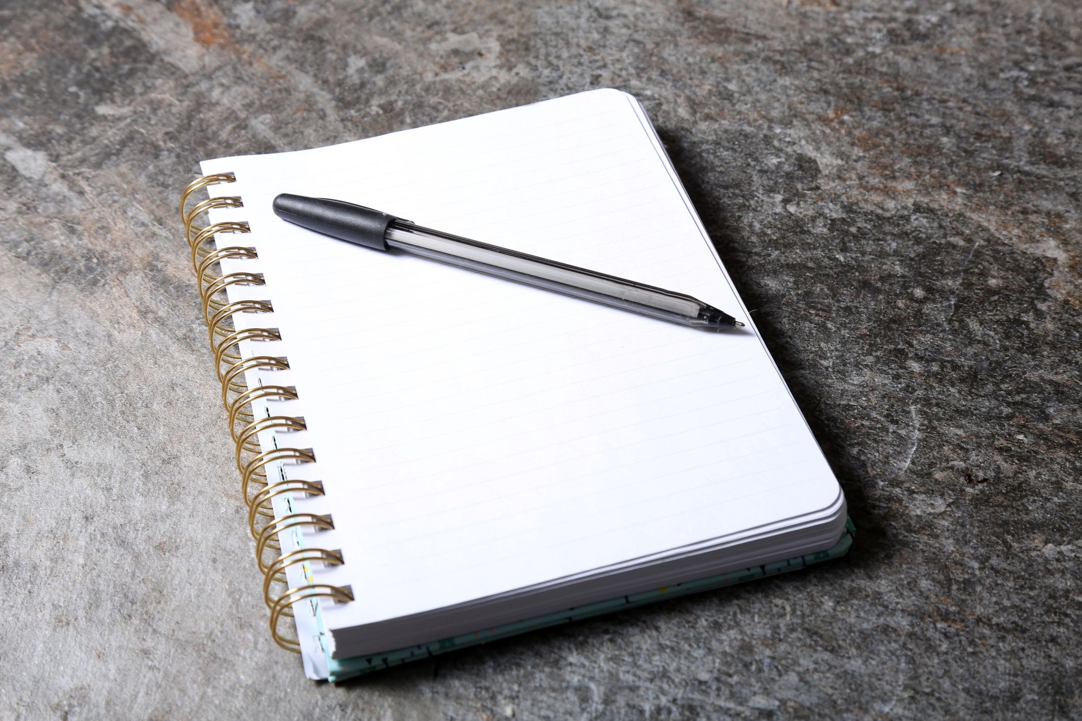 Notebook with blank page and pen on a dark surface